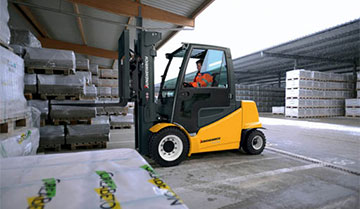 Operator Driving a EFG 535k-S50 Electric Pneumatic Lift Truck with Materials Outdoors